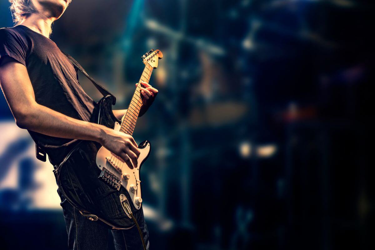 ステージでギターを弾く男性ミュージシャン。