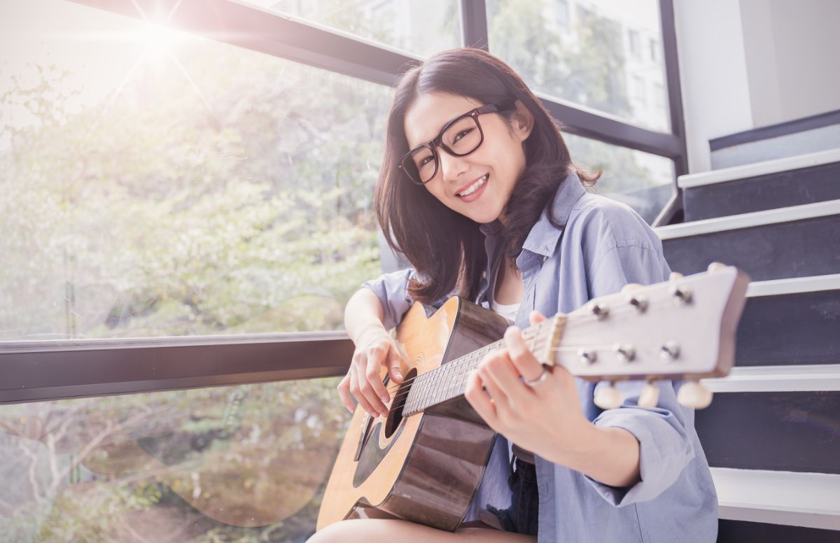 窓際でギターを弾く若い女の子