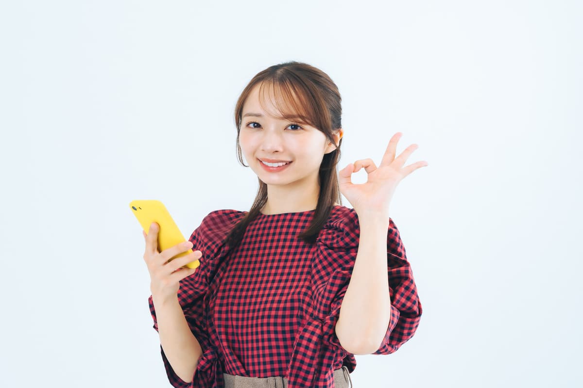 スマートフォンを持ってほほ笑む女性