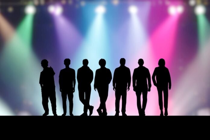 ステージ上の7人の男性アイドルとカラフルなスポットライト