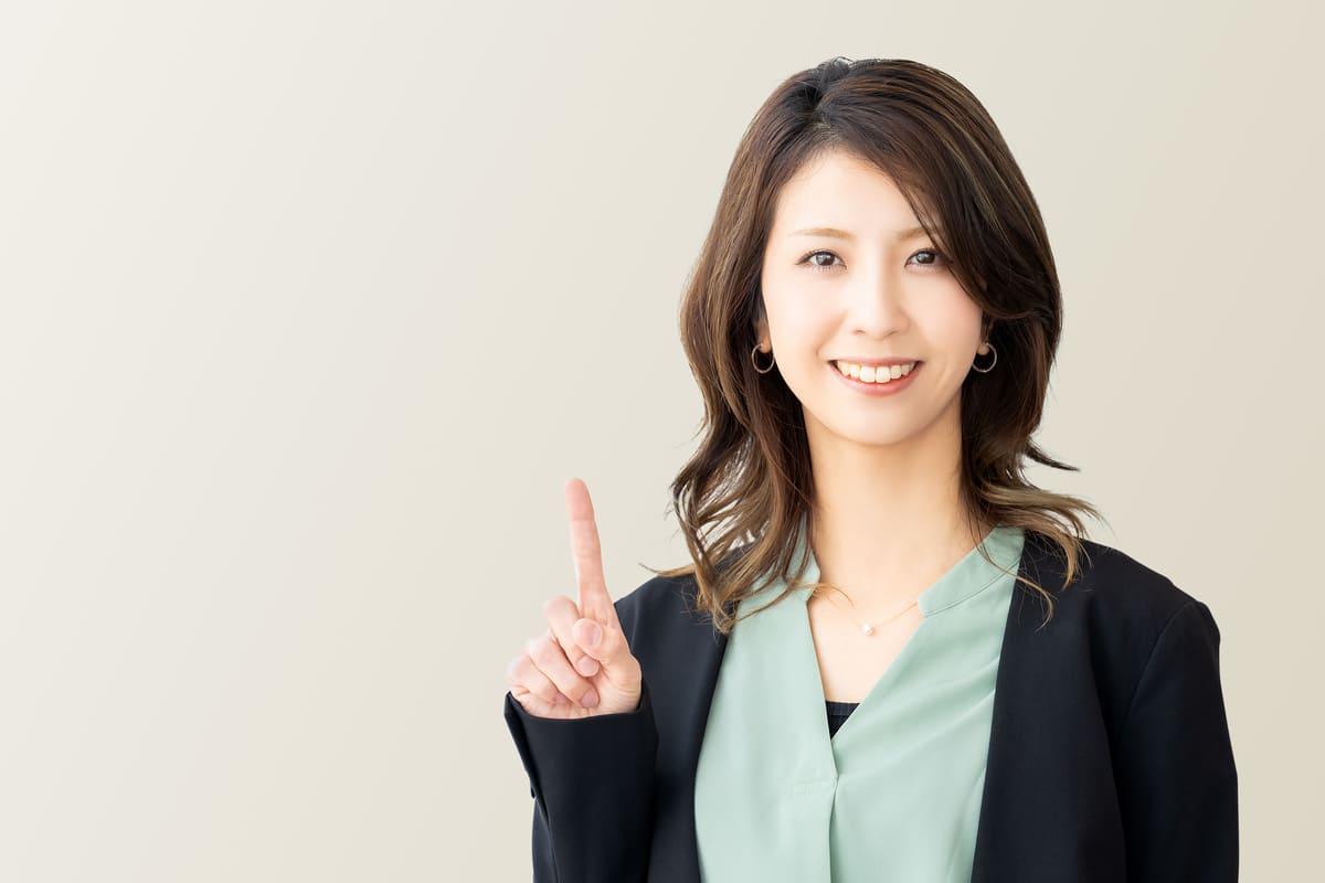人差し指を立てて案内するビジネスウーマン