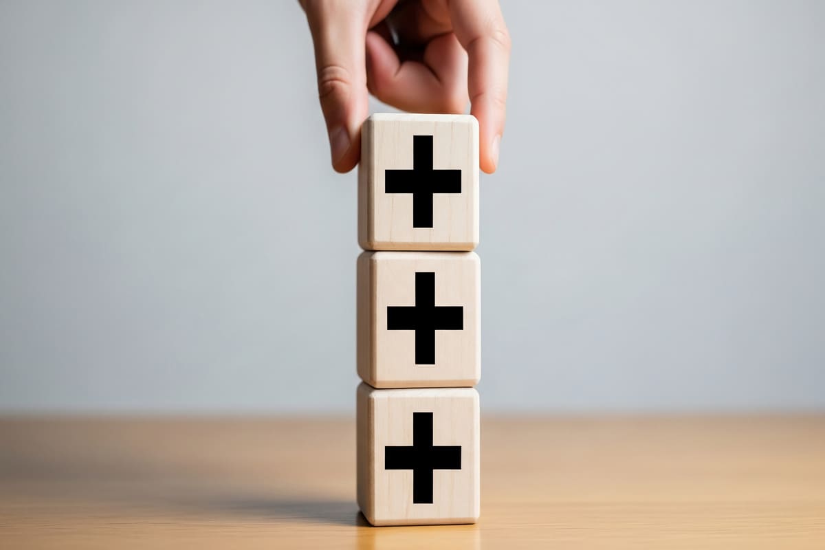 プラスの積み木を積み上げる手