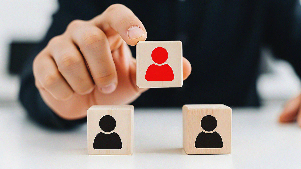 人型の積み木をひとつ持ち上げている手