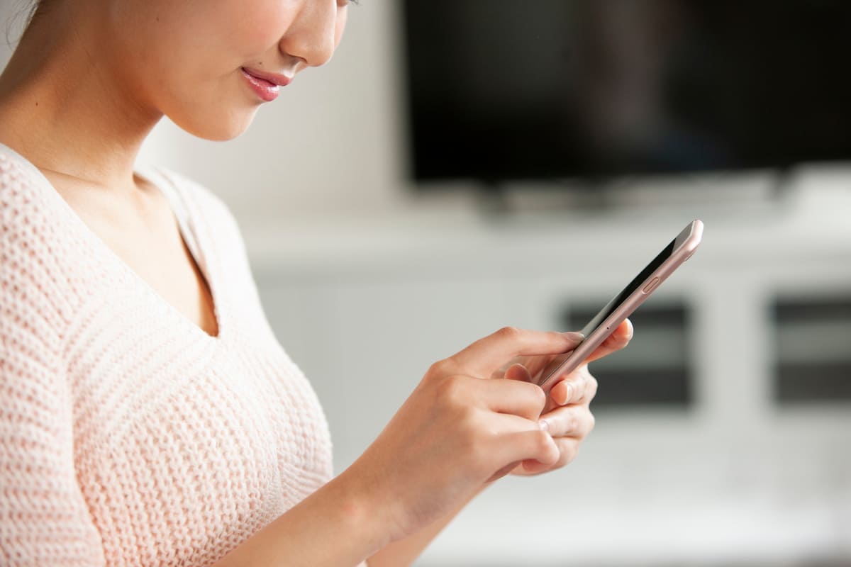 TVの前でスマホ検索している女性