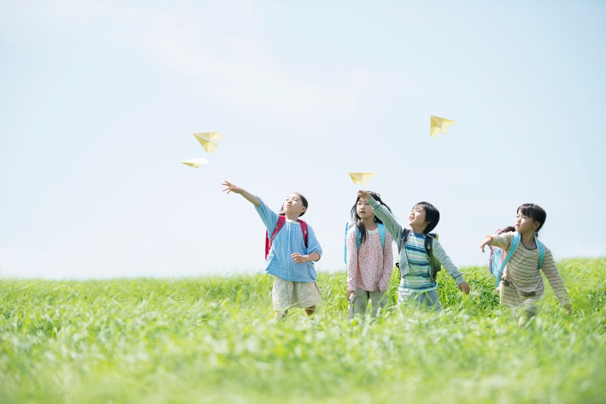 草原で飛行機を飛ばす小学生