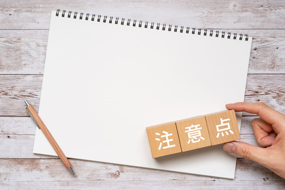 注意点と書かれたブロック、ノート、ペン、手