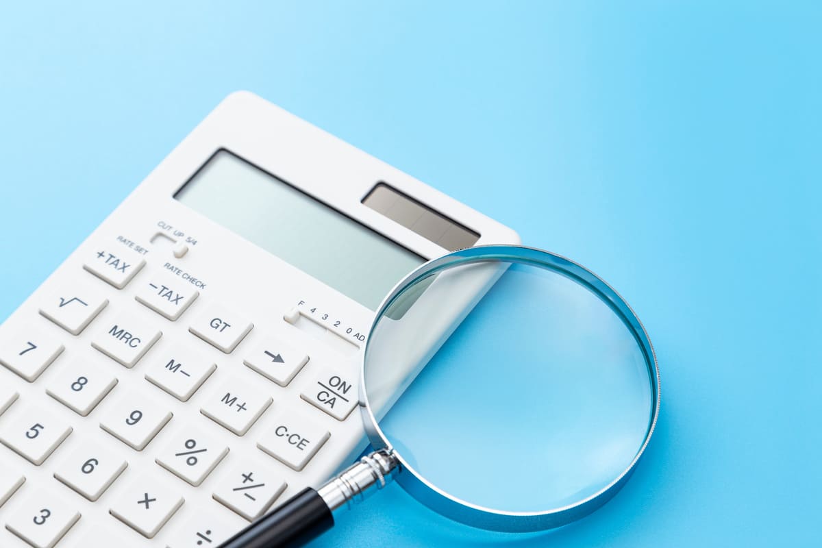 青背景に電卓と虫眼鏡