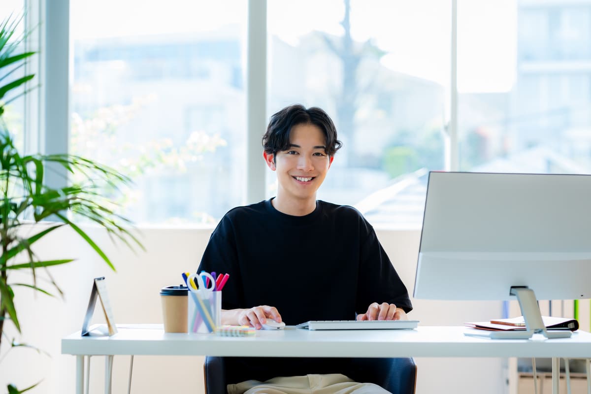 デスクでほほ笑む男性クリエイター