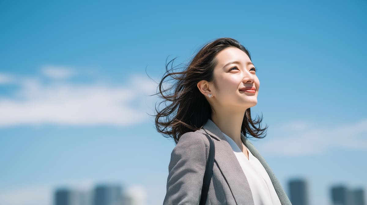 青空の下で都会を背景に立つビジネスウーマン