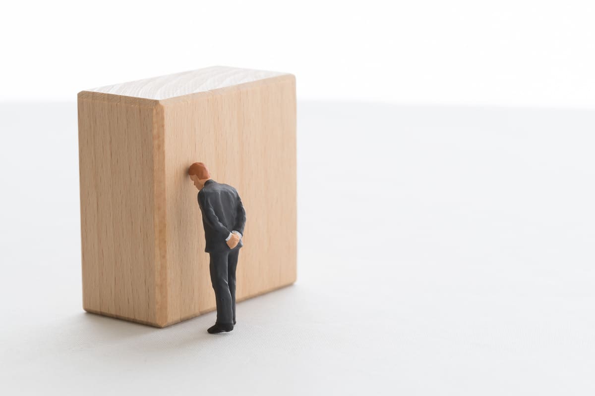 壁に頭を付けている男子学生のイメージ