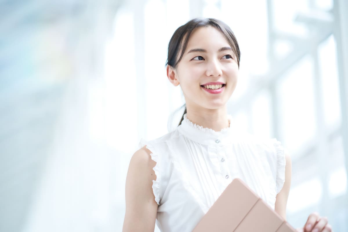 笑顔でパソコンを持って移動中の女子大生