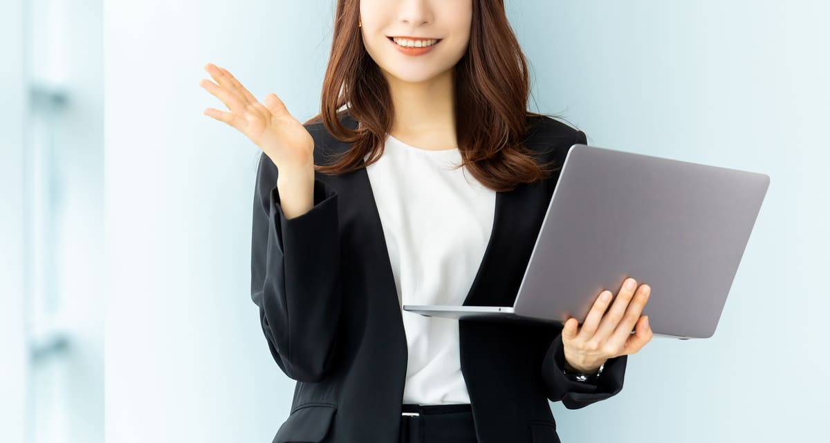 パソコンを持って案内をする笑顔の女性