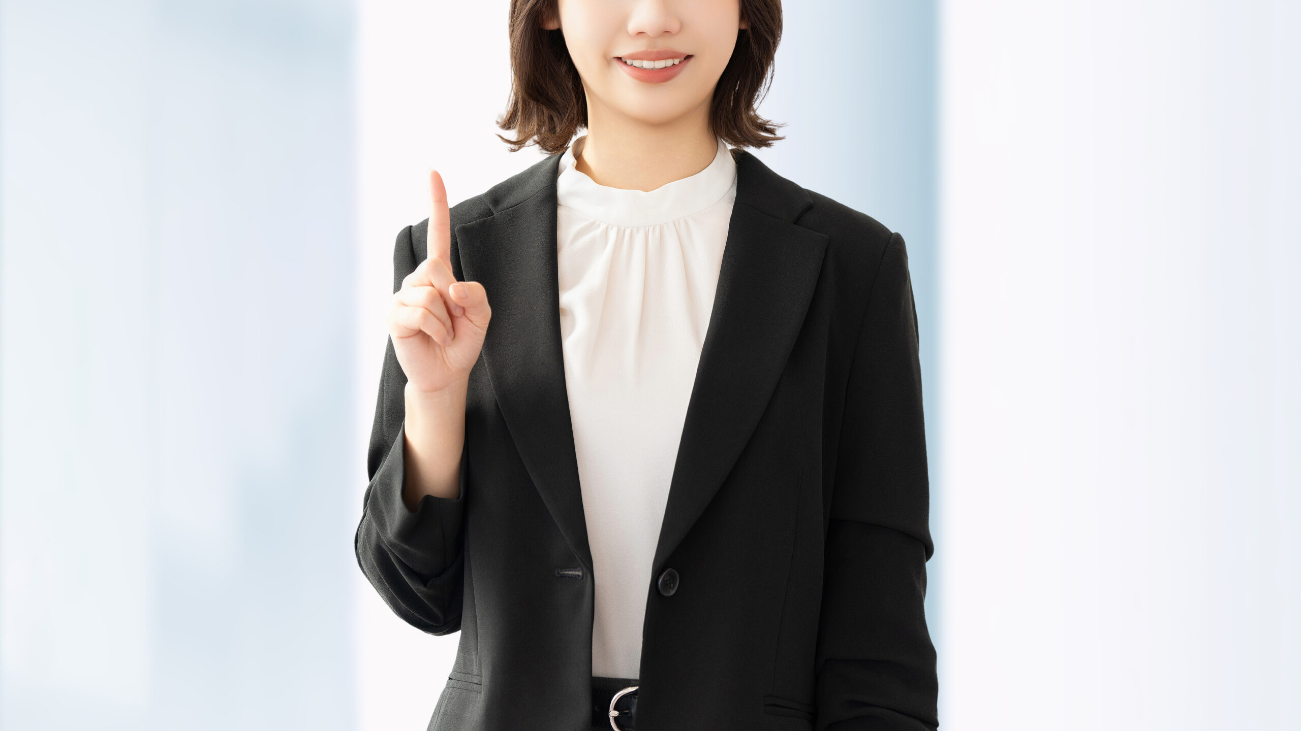 人差し指を立てて案内する笑顔の女性・ビジネスウーマン