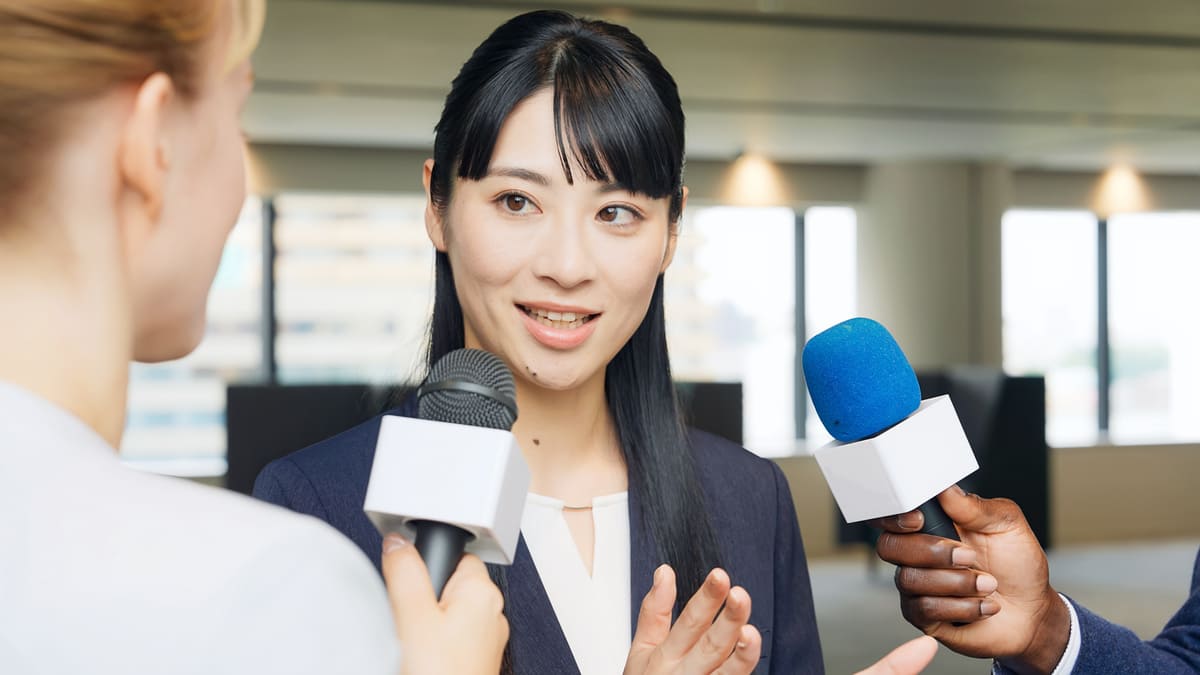 メディアに囲まれてインタビューを受ける女性